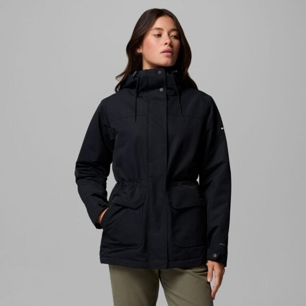Damen trägt schwarze Columbia Idyllwood Omni Tech Winterjacke mit Kapuze, ideal für kalte Wintertage, auf neutralem Hintergrund.