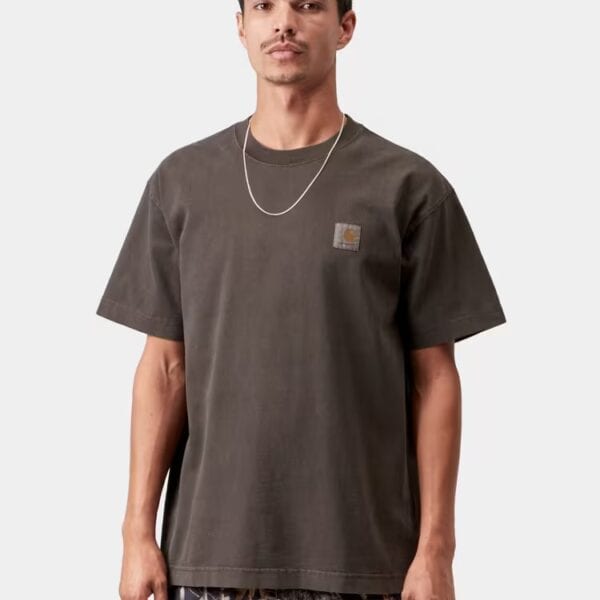 Mann trägt ein braunes Carhartt Wip Vista Vintage T-Shirt mit Rundhalsausschnitt und Logo auf der Brust, kombiniert mit Camouflage-Hose, auf weißem Hintergrund.