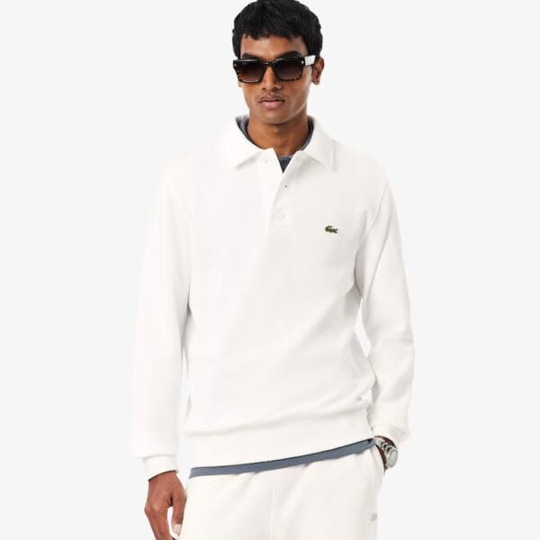 Mann trägt weißen Lacoste Rippstrick Polo Pullover mit Logo, Sonnenbrille und dunklen Haaren, stilvoller Look, Mode, Freizeit.