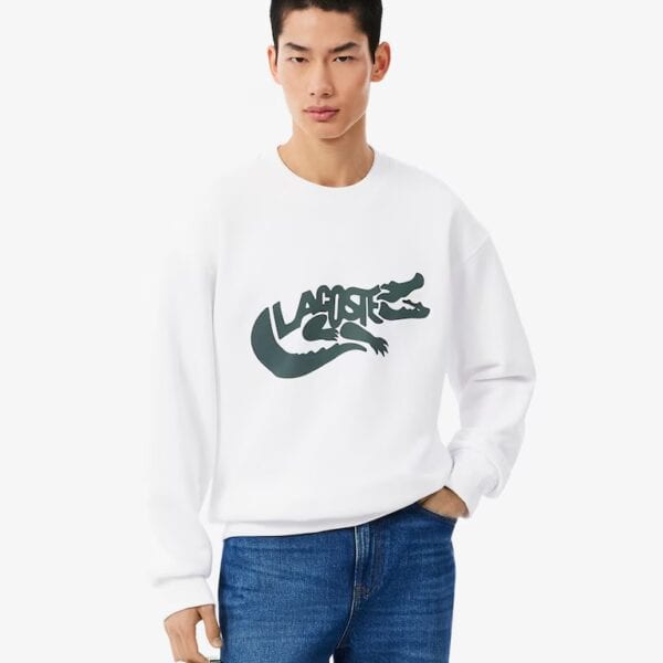 Mann trägt weißen Lacoste Pullover mit grünem Krokodil-Logo, casual Look, Mode für Herren, sportlich, bequem, hochwertig, stilvoll, Freizeitkleidung, Trend.