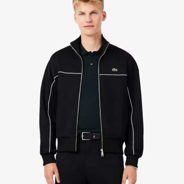 Mann trägt die schwarze Lacoste Interlock-Pique Jacke mit weißen Kontrastnähten, ideal für sportliche Freizeitaktivitäten.