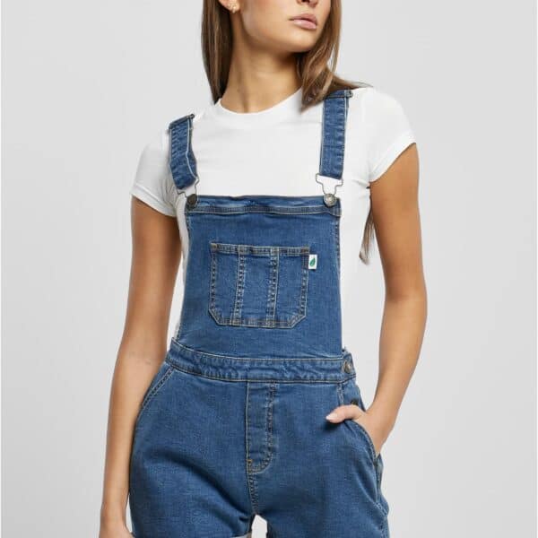 Damen in blauen kurzen Latzhosen mit weißen T-Shirt, modischer Streetwear-Look, urbaner Stil, Freizeitmode, Mode für Damen, trendige Shorts, Denim-Shorts, Sommeroutfit, casual.