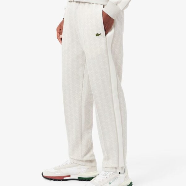 Weiße Lacoste Trackhose mit Monogramm-Design, bequem und sportlich, ideal für Freizeit und Sport, mit elastischem Bund und seitlichen Taschen.