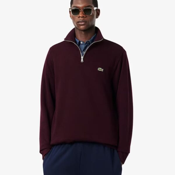 Mann trägt braunen Lacoste Rippstrick Half Zip Pullover mit Reißverschluss, Sonnenbrille und dunklen Hosen, stilvoll und sportlich.