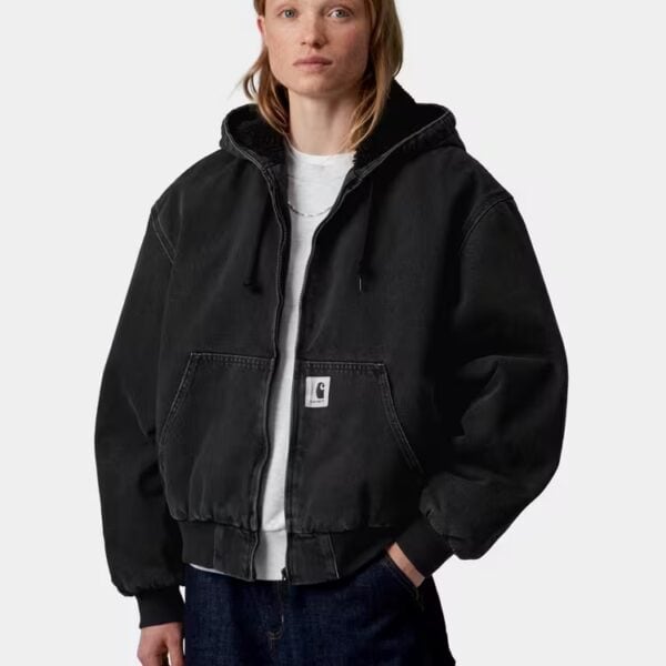 Dame trägt schwarze Carhartt Wip Winterjacke mit Kapuze, lässiger Stil, Wintermode, urbaner Look, bequem, warm, modisch, Freizeitjacke, Streetwear, Winteroutfit.