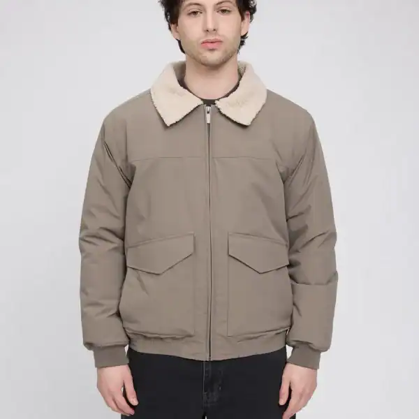 Männlicher Model trägt eine beige-braune Winterjacke mit Fellkragen, ideal für kalte Wintertage, auf neutralem Hintergrund.