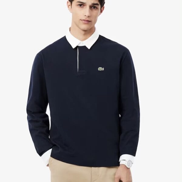 Junger Mann trägt ein Lacoste Rugby Polo Langarmshirt in Dunkelblau mit weißem Kragen, ideal für sportliche und elegante Freizeitlooks.