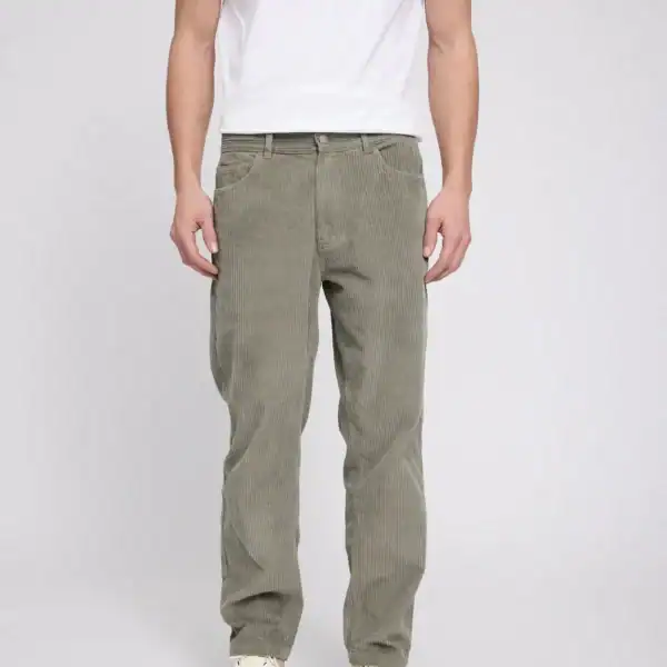 Männliche Person trägt grüne Cordhose mit 5 Taschen, kombiniert mit weißem T-Shirt und Sneakers, auf neutralem Hintergrund.