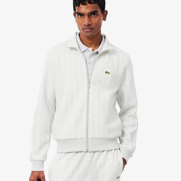 Mann trägt weiße Lacoste Jacquard Track Jacke mit Monogramm-Design, sportlich und stilvoll, auf weißem Hintergrund.